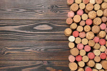 Many corks of wine bottles on wooden table, top view. Space for text