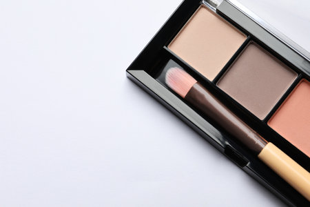 Beautiful eye shadow palette with brush on white table, top view. Space for textの写真素材