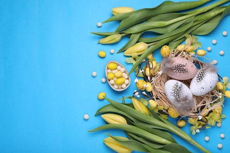 Flat lay composition with beautiful flowers and eggs on light blue background, space for text....
