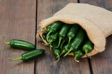 Sack with jalapeno peppers on wooden table