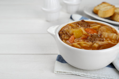 Tasty cabbage soup with meat and carrot on white wooden table, closeup. Space for textの写真素材