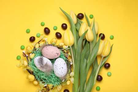 Flat lay composition with beautiful flowers and eggs on yellow background. easter celebrationの写真素材