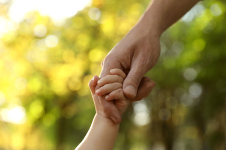 Daughter holding father's hand outdoors, closeup. happy familyの写真素材