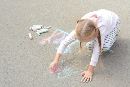 Little child drawing happy family with chalk on asphaltの写真素材