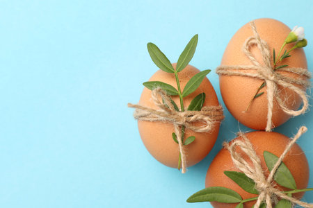 Festively decorated chicken eggs on light blue background, flat lay with space for text. happy...