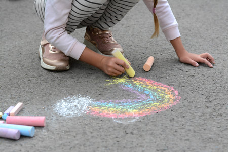 Little child drawing rainbow with chalk on asphalt, closeupの写真素材