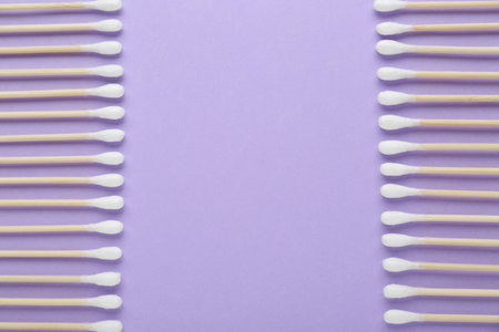 Many wooden cotton buds on violet background, flat lay. Space for text
