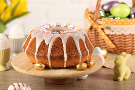 Delicious Easter cake decorated with sprinkles near eggs and rabbit figure on wooden table