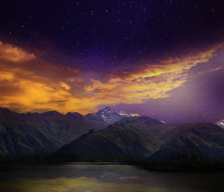 Fantastic sky with many stars and beautiful clouds over mountainsの写真素材