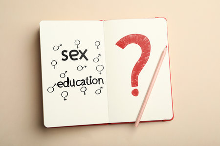 Notebook with text Sex Education, question mark, female and male gender signs on beige background, top viewの写真素材