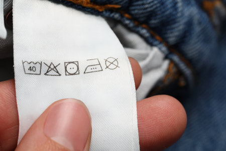Woman holding clothing label on jeans garment, closeupの写真素材