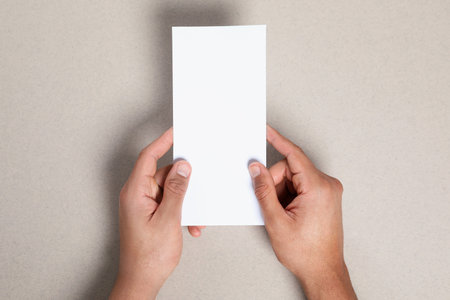 Man holding flyer on gray background, closeup. Mockup for designの写真素材