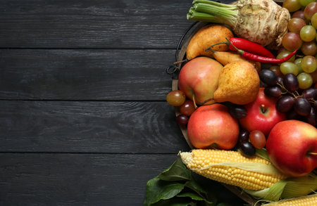 Different fresh vegetables and fruits on black wooden table, top view with space for text. farmer...