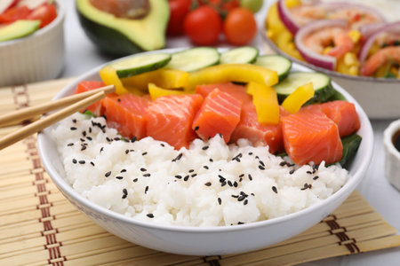Delicious poke bowl with salmon, rice and vegetables on table, closeupの写真素材