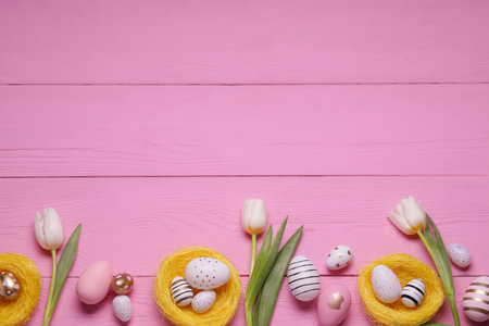 Flat lay composition of painted Easter eggs and tulip flowers on pink wooden table. Space for textの写真素材