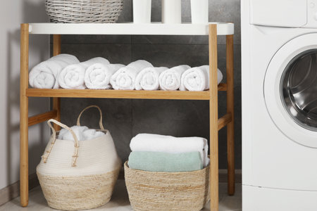 Wooden shelf and wicker baskets with soft terry towels in bathroomの写真素材