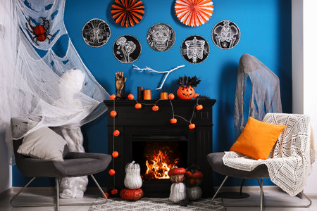 Jack-o'-lanterns and different Halloween decorations on black fireplace near blue wallの写真素材