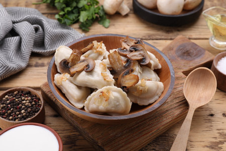 Delicious dumplings (varenyky) with potatoes, onion and mushrooms served on wooden tableの写真素材
