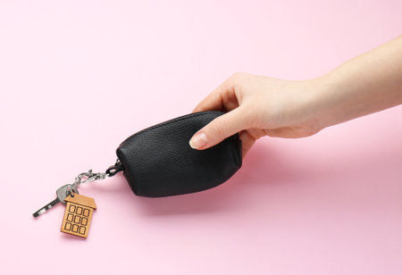 Woman holding leather case with key on pink background, top viewの写真素材