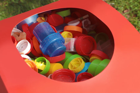 Different colorful bottle caps in red bin. plastic recyclingの写真素材