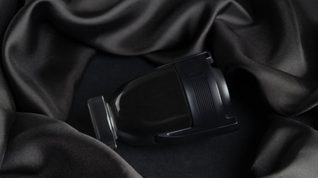 Bottle of luxurious perfume and silk fabric on black background