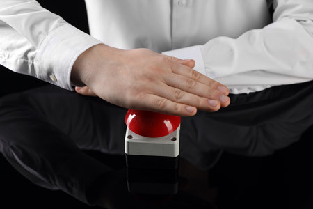 Man pressing red button of nuclear weapon on black background, closeup. War conceptの写真素材