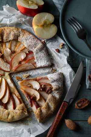 Delicious apple galette with pecans and knife on wooden table, flat layの写真素材