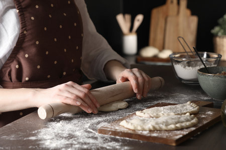 Woman rolling dough for chebureki at wooden table, closeupの写真素材