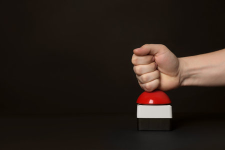 Man pressing red button of nuclear weapon at black background, closeup with space for text. War conceptの写真素材