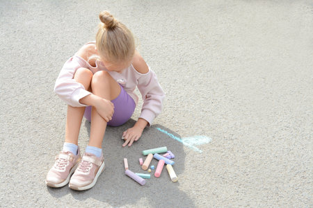 Little child drawing flower with chalk on asphalt, space for textの写真素材