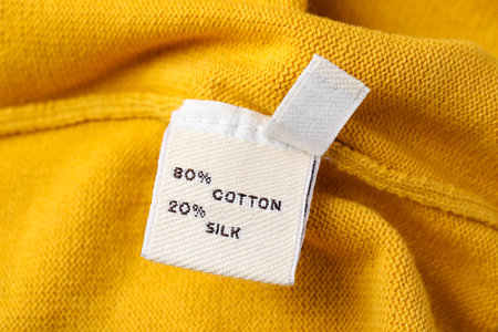 Clothing label on beautiful yellow garment, closeupの写真素材