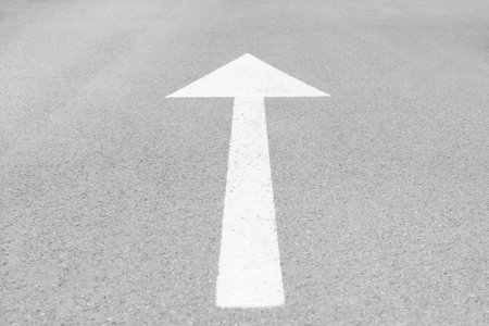 White arrow painted on asphalt road in cityの写真素材