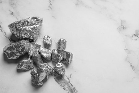 Pile of silver nuggets on white marble table, flat lay. Space for textの写真素材
