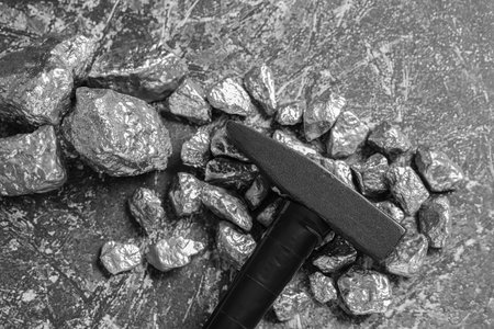 Pile of silver nuggets and hammer on gray textured table, flat layの写真素材