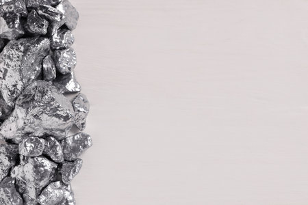 Pile of silver nuggets on white wooden table, flat lay. Space for textの写真素材