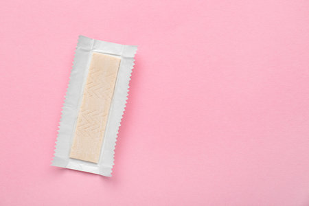 Unwrapped stick of chewing gum on pink background, top view. Space for text