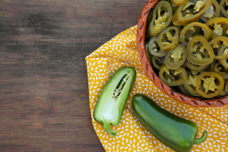 Fresh and pickled green jalapeno peppers on wooden table, top view. Space for textの写真素材
