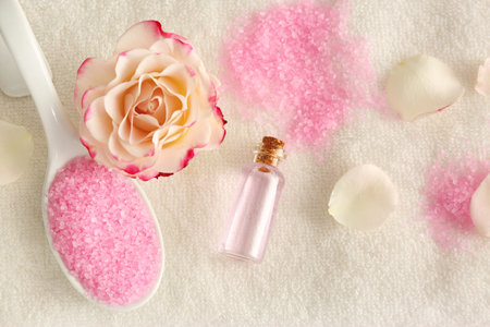 Aromatic sea salt, beautiful flower and petals on white towel, flat layの写真素材