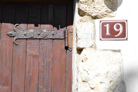 Plate with house number nineteen near door on stone wall outdoorsの写真素材