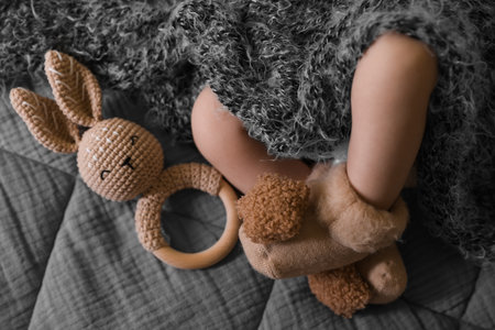 Adorable newborn baby with gray fluffy blanket and teething toy in bed, closeupの写真素材