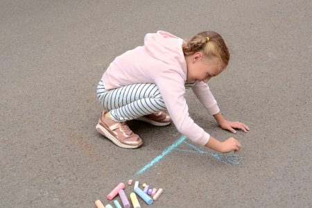 Little child drawing happy family with chalk on asphaltの写真素材