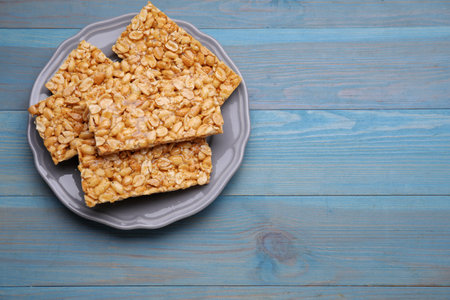 Delicious peanut bars (kozinaki) on light blue wooden table, top view. Space for textの写真素材