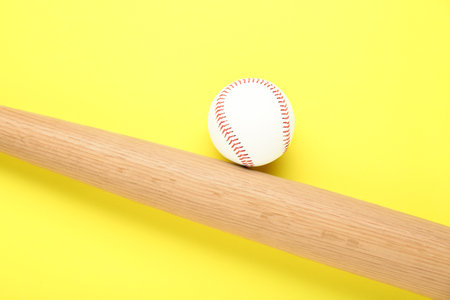 Wooden baseball bat and ball on yellow background, flat lay. sports equipmentの写真素材