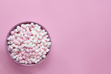 Bowl with delicious marshmallows on pink background, top view. Space for textの写真素材