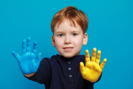 Little boy with hands painted in Ukrainian flag colors on light blue background. Love Ukraine conceptの写真素材