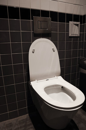 Clean ceramic toilet bowl near tiled wall indoorsの写真素材