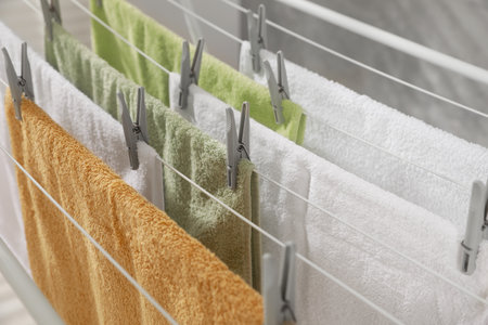 Clean terry towels hanging on drying rack, closeup