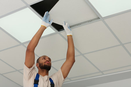 Electrician repairing ceiling light indoors, low angle view. Space for textの写真素材