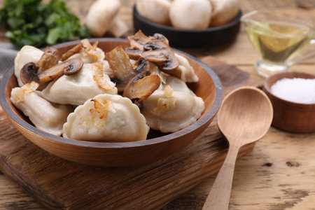 Delicious dumplings (varenyky) with potatoes, onion and mushrooms served on wooden tableの写真素材