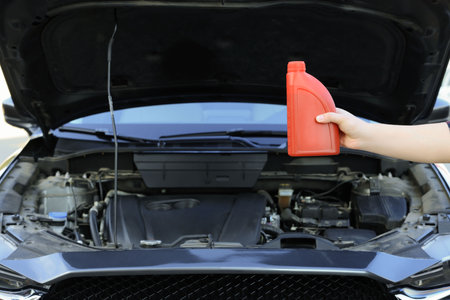 Man holding bottle of motor oil near car, closeup. Space for textの写真素材